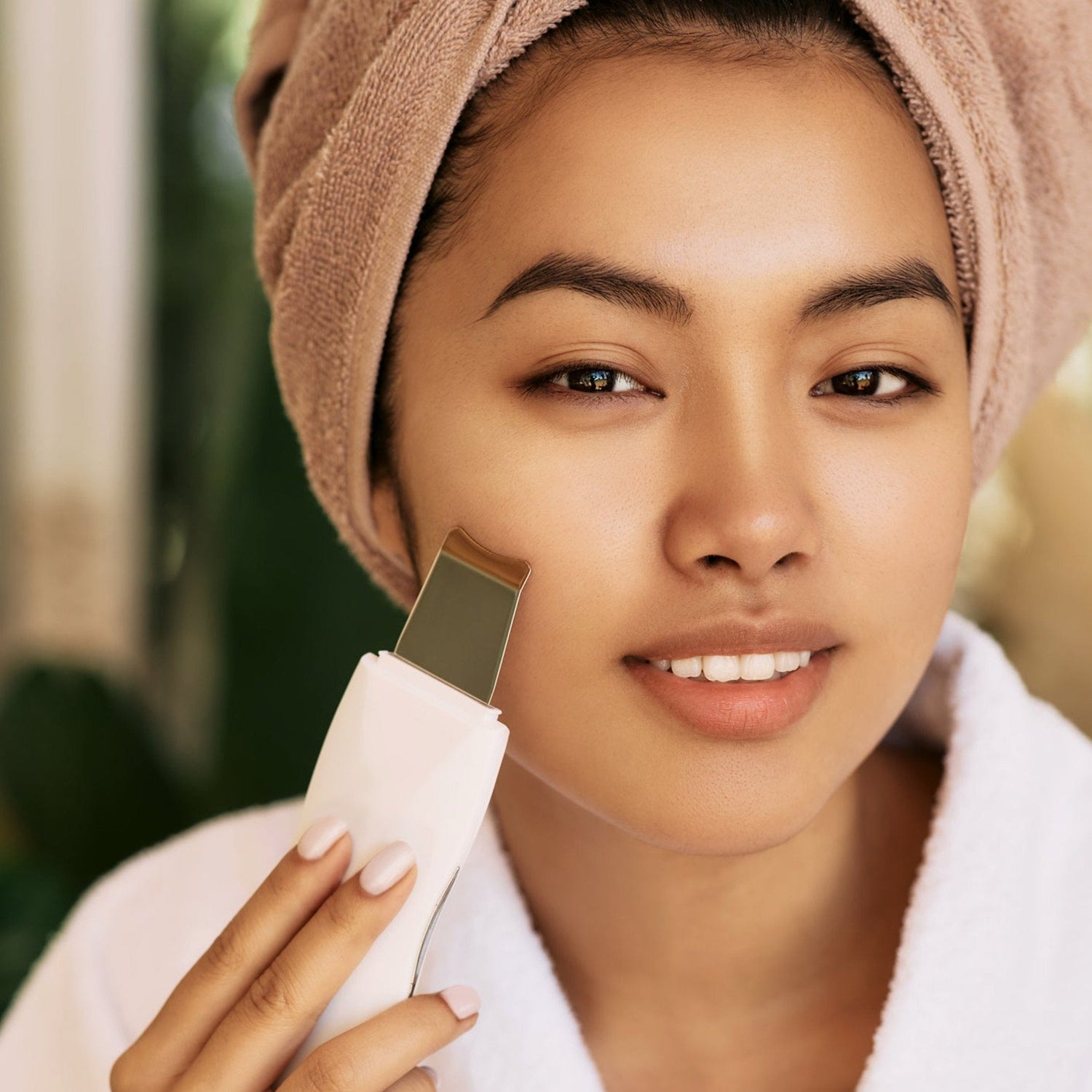 Woman using device for natural EMS facial skin care.